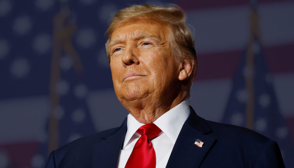 Donald trump standing in front of a bunch of american flags